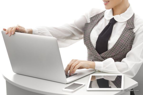 Close-up on arms of confident business woman working on laptop tablet and phone, selective focus