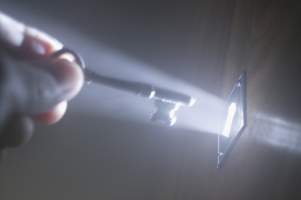 Person putting key in keyhole with light coming from it