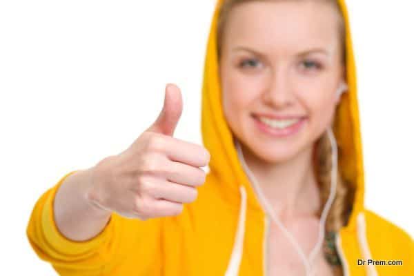 Closeup on happy teenager girl in earphones showing thumbs up