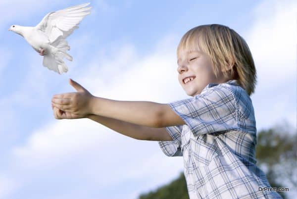 Little boy releasing a white pigeon in the sky