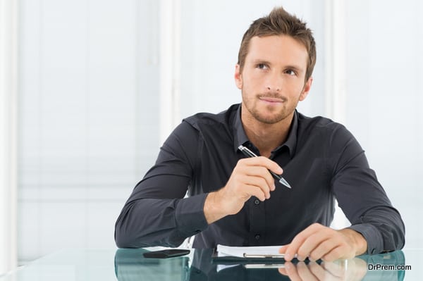 Young Businessman Thinking and Wondering While Writing a Paper