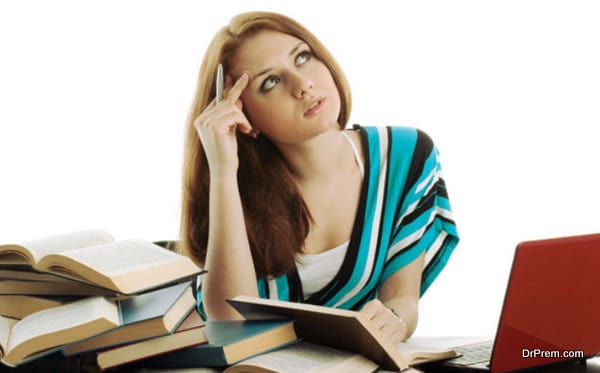 Young woman sitting at a desk among books and laptop on a white background