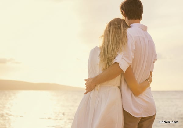 Happy romantic couple on the beach at sunset embracing each othe