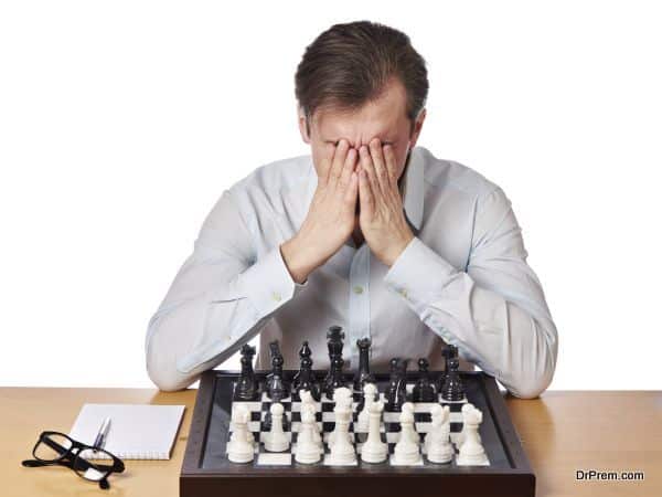 Man covered face with his hands in heavy chess game