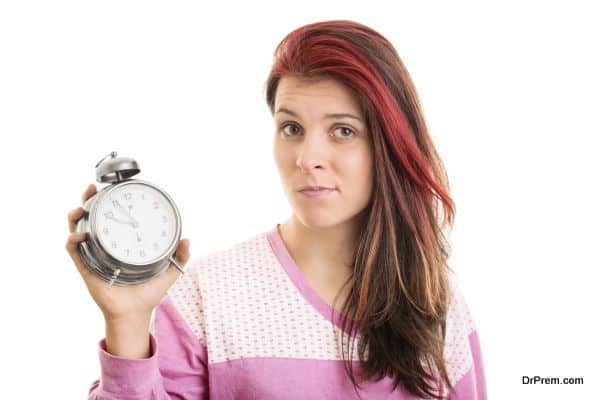 Young girl in pyjamas holding an alarm clock