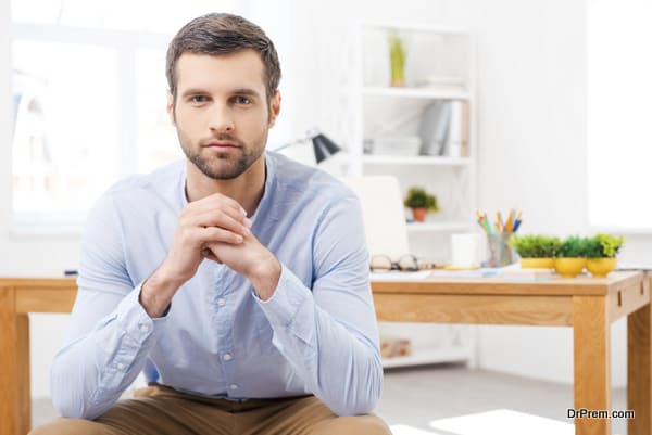 Confident and creative. Handsome young man in shirt sitting in f