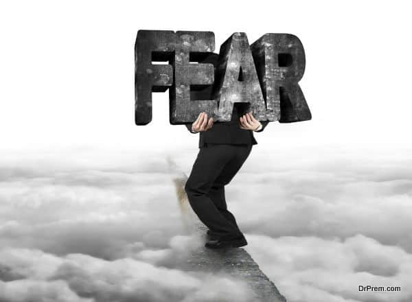 Man carrying fear concrete word on ridge with cloudy