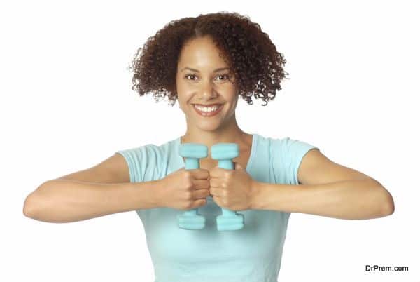 Athletic, healthy, smiling young woman lifting small weights