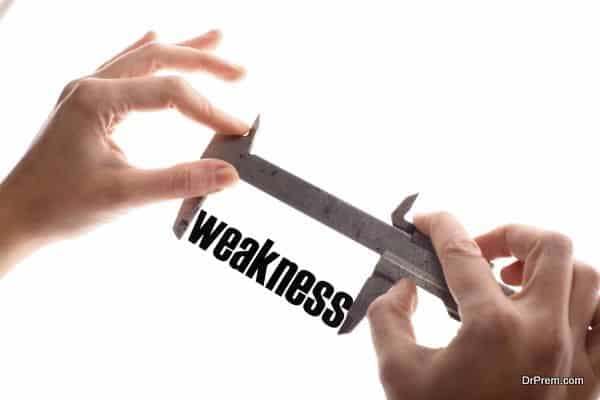 Color horizontal shot of two hands holding a caliper and measuring the word "weakness".