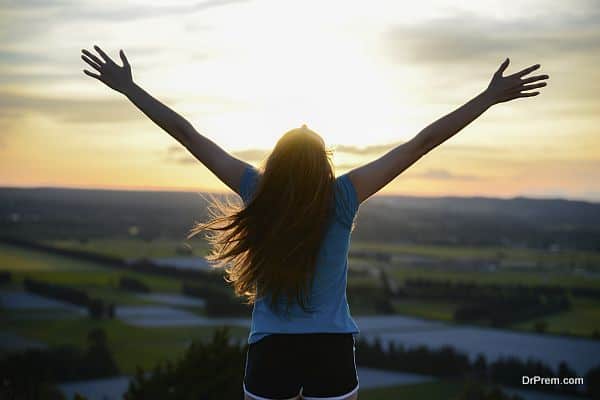 happy young woman outdoor rising hands and looking at landscape on sunset