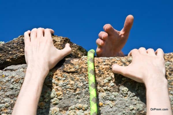 Hands of climber on brink of rock needing the help