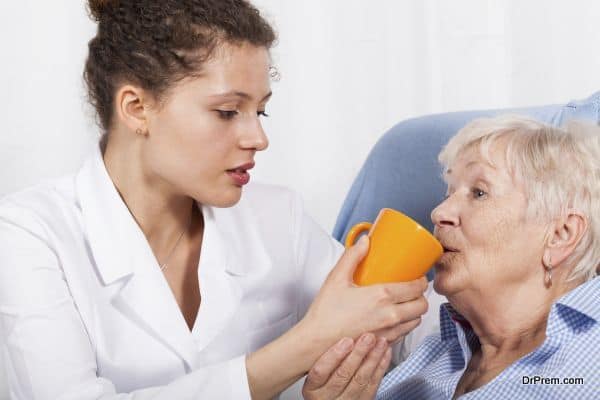 Nurse gives something to drink old woman