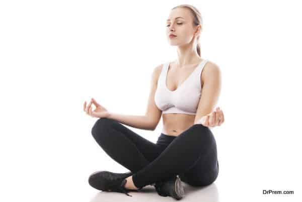 Young woman sitting in lotus position isolated over white background