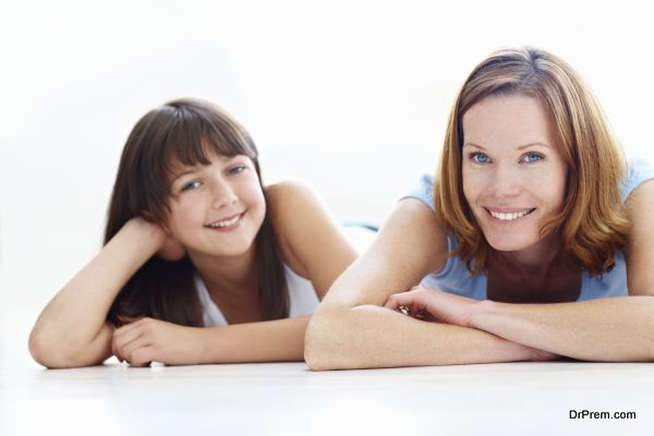 Portrait of happy mother and daughter lying on floor smiling on white