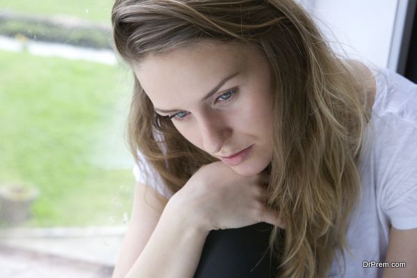 Close up portrait of a young woman sitting alone by window