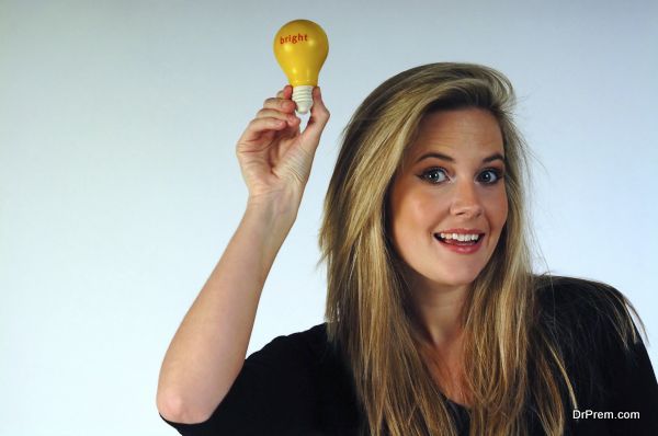 Young woman holding aloft a lightbulb.