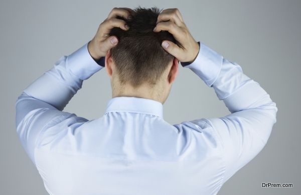 Stressed businessman with headache standing back to camera
