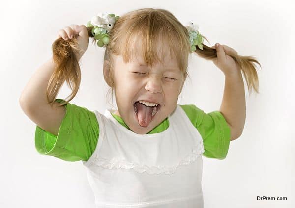 Head and hands shot of Little girl sticking out her tongue at the camera for fun