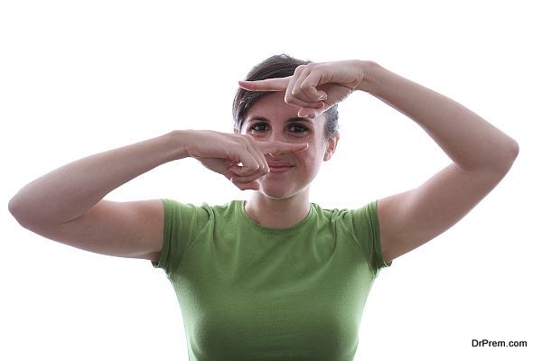 Caucasian female is looking at a subject through her fingers