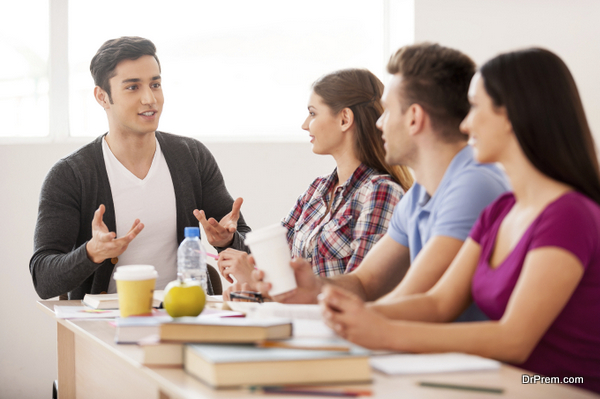 Cheerful students. Four cheerful students talking to each other while sitting at the desk