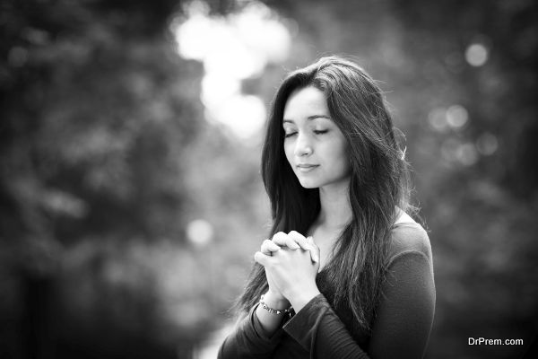 Woman hands praying with a blible in his legs Outdoors black and white