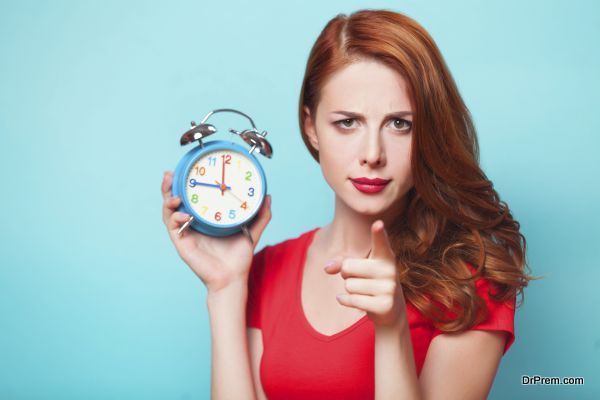 Redhead girl with alarm clock on blue background.