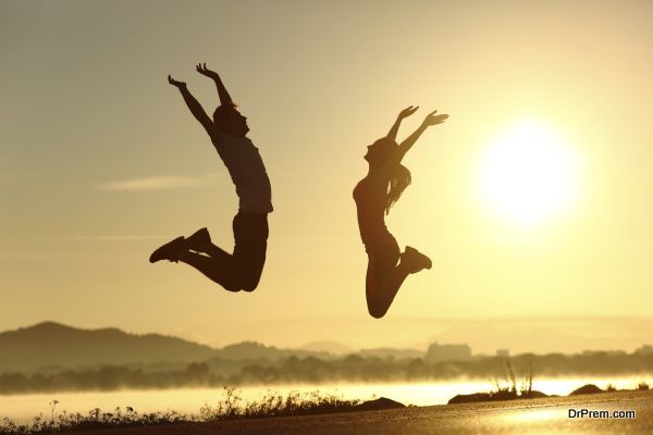 Fitness couple jumping happy at sunset