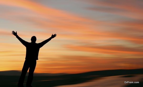 Man with outstretched arms facing a beautiful sunset.