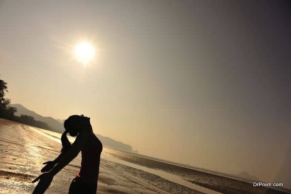 cheering young woman open arms on sunrise beach