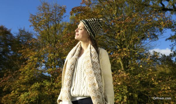 Portrait of an attractive woman in sweater and hat enjoying the sun on an autumn calm day