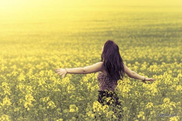 Beautiful woman in meadow of yellow flowers from behind