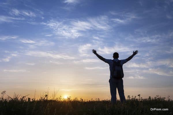 Silhouette of man with arms raised up and beautiful sky