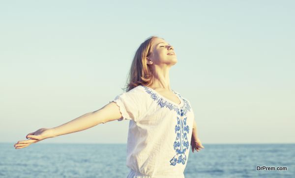 happy young woman open her arms to the sky and sea and enjoying life