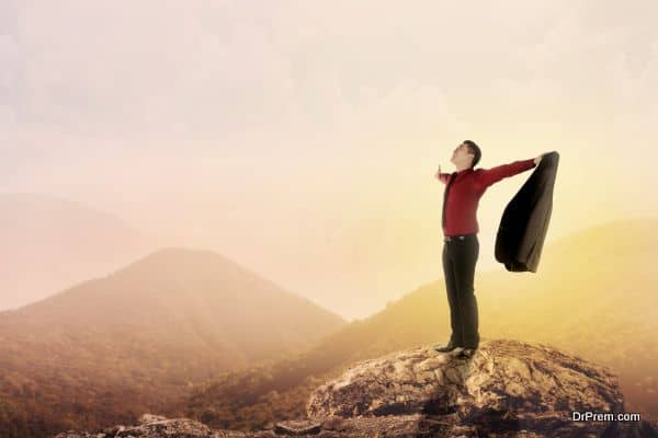 Asian business man standing on the top of mountain, raise hand and open his suit