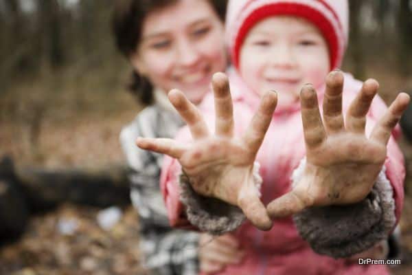 Mother and her four years old daughter in park. Child showing her dirty hands.