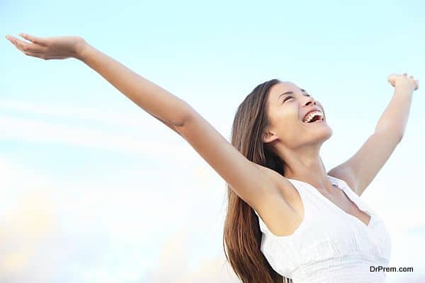 Happiness bliss freedom concept. Woman happy smiling joyful with arms up dancing on beach in summer during holidays travel. Beautiful young cheerful mixed race Asian Chinese / Caucasian female model outdoor.