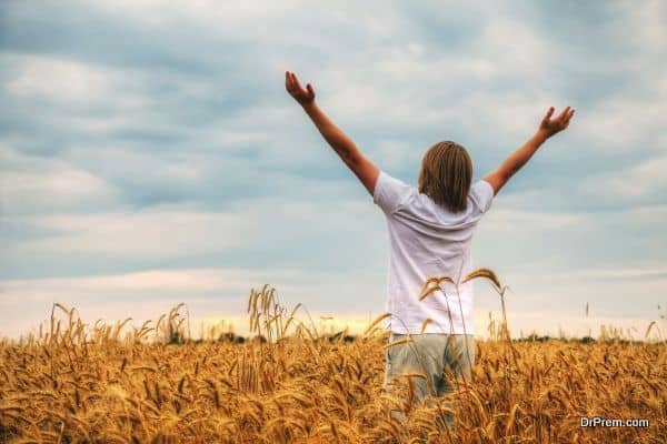 Young man staying with raised hands at sunset time