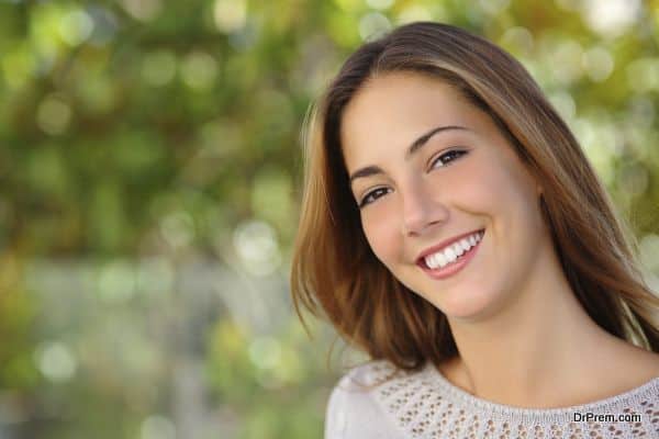 Beautiful woman facial with a perfect white smile outdoor with a green background