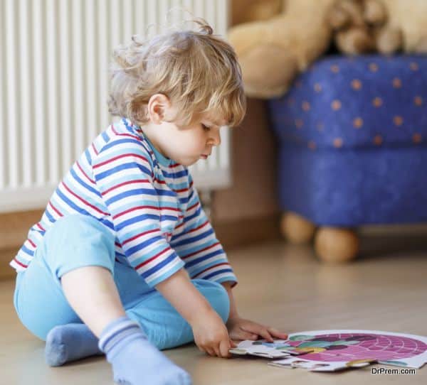Little cute blond boy playing with puzzle game at home