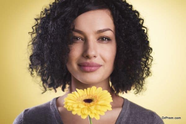 Pretty girl smiling and holding a blossom in her hand.