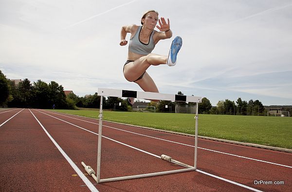 A young athlete jumping over a hurdle