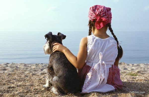 beautiful little girls embracing her dog looking at the sea