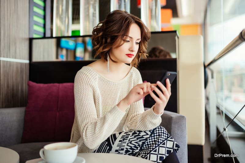 woman sitting in cafe at table and use smartphone