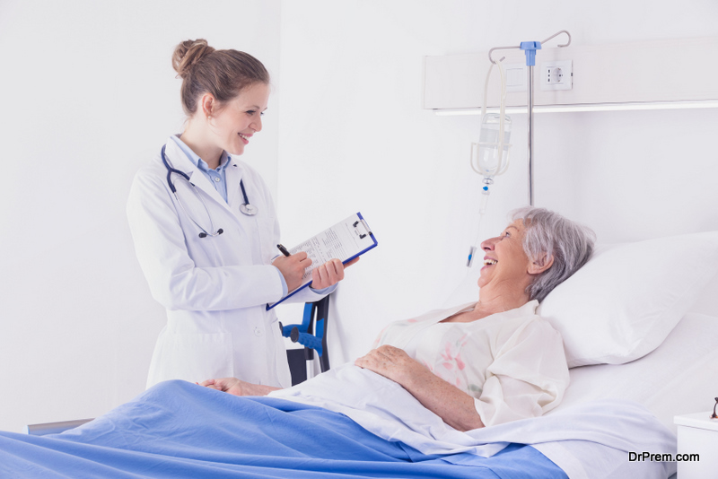 Doctor or nurse chatting to a senior woman patient during ward rounds at a hospital taking notes as they smile at each other