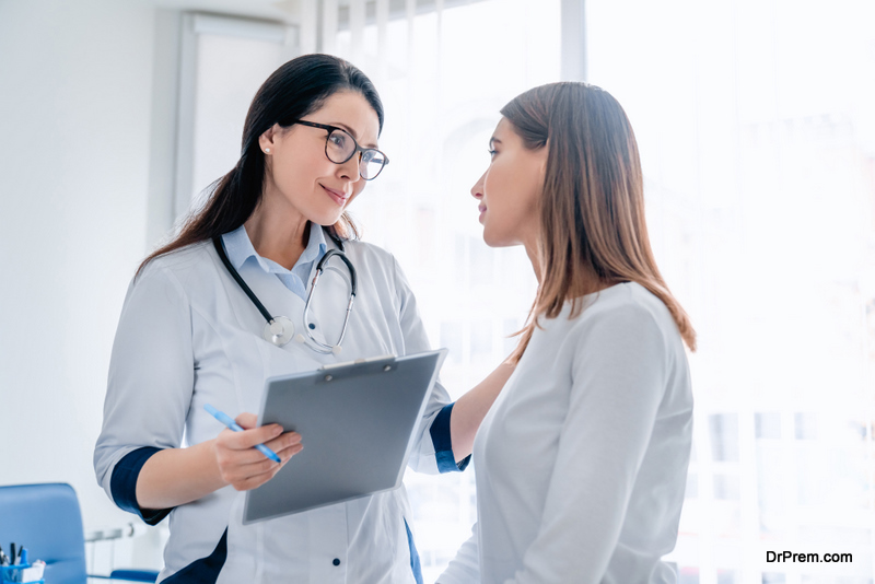 Doctor talking to female patient in working cabinet at hospital