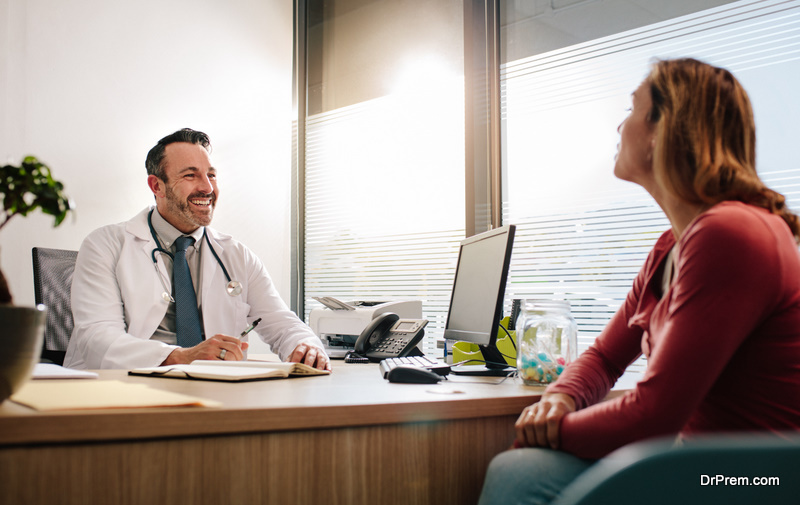 Doctor talking with female patient sitting across the desk in clinic