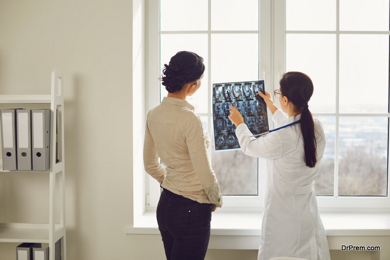 Doctor woman with x-ray talking client sitting at a table in a clinic office