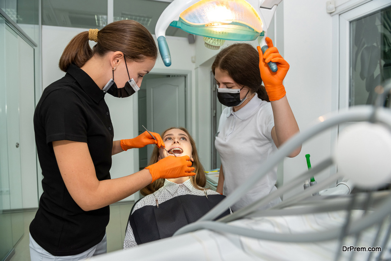 Female dentist and young assistant doing repairing patient tooth in dental ambulant. Doctor practice