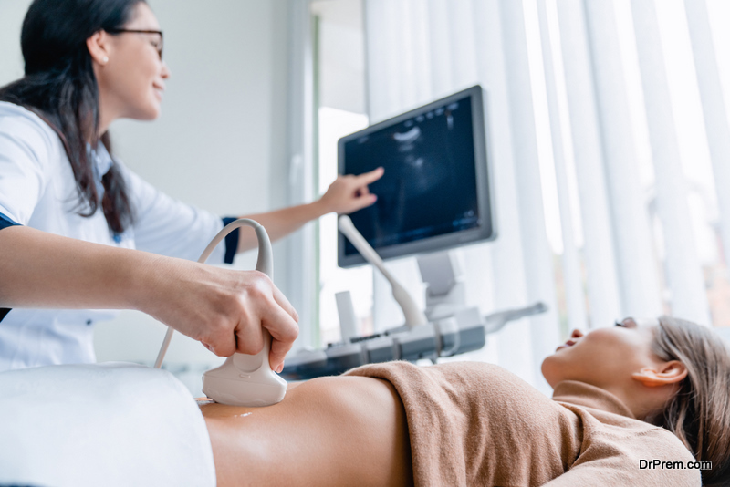 Mid adult female doctor using ultrasound scanner