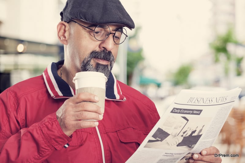 Middle aged man reading newspaper with glasses